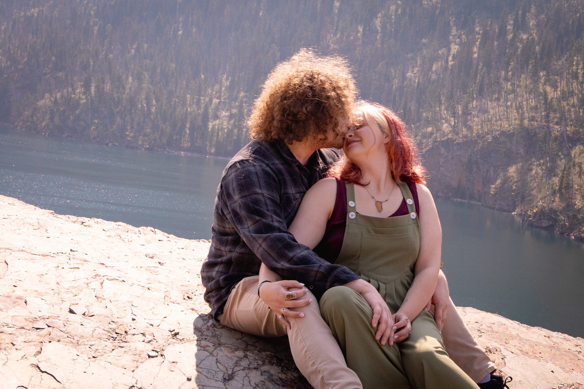 Couple sharing a quiet moment seated on a cliff edge above a lake